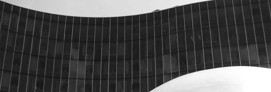 Black and white detail of a curved glass facade.