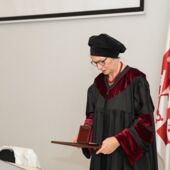 Sigrid Weigel im Talar blickt herab auf ihre Urkunde und Medaille
