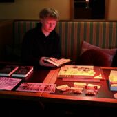 Nicola Chodan sitzt an einem Auslagentisch mit Informationsbroschüren und Büchern.