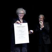Sigrid Weigel happily holds her honorary doctorate certificate in the camera