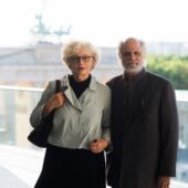Portrait photo of Sigrid Weigel and Homi Bhabha, with an out-of-focus Brandenburg Gate in the background