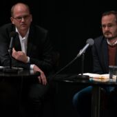 Stefan Willer spricht in einem Mikrofon, neben ihm sitzt Jonas Lüscher hinter einem zweiten Mikrofon