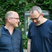 Stefan Willer and Andreas Bernard stand next to each other in the garden and talk.