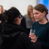 Hannah Markus talking to a visitor, holding a glass in her hand