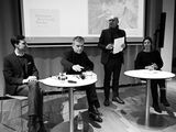 Lukas Laier, Christoph Hesse and Anja Kunzmann sit at two bistro tables, with Claude Haas standing between them and speaking to the audience. Behind him, a picture of Hermann Borchardt can be seen on a screen.