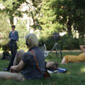 Four people lie, sit and stand on a lawn and listen to Cord Riechelmann’s guided tour using a headset.