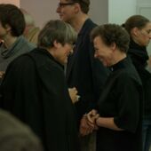 Eva Geulen speaks with a participant and smiles, surrounded by many other participants