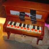 Close-up of a very small wooden mini piano with orange dots on its few keys.
