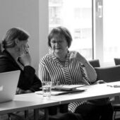 Schwarz-weiß Fotografie von zwei Konferenzteilnehmerinnen, sie sitzen und besprechen sich.
