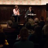 Long shot of Judith Schalansky and Alexandra Heimes at the reading table, with audience in foreground
