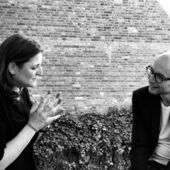 Black and white photograph of Gertraud Klemm und Claude Haas. They are engaged in conversation, Gertraud Klemm gestures with both hands.