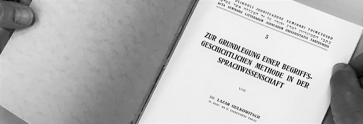 Black and white photo of the opened book "Zur Grundlegung einer begriffsgeschichtlichen Medothe in der Sprachwissenschaft" by Lazar Gulkovich with fingers at the margins.