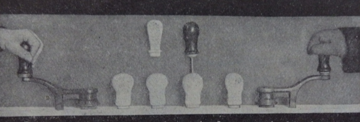 Schwarz-weißes Foto. Eine Reihe von Prototypen für Griffformen. Am linken und rechten Rand des Bildes ist jeweils eine Hand, die jeweils einen Griff umfasst und ausprobiert.